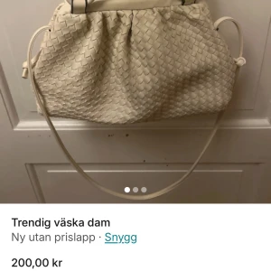 Beige flätad handväska - Trendig beige handväska med flätat mönster och röd insida. Väskan har en lång axelrem och en stilren design, perfekt för att lyfta din outfit. Acelremmen är även justerbar och går att ta av💗 kom privat för fler frågor💗