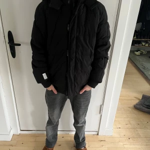 Svart jacka från Abercrombie Kids - Svart Abercrombie Kids-jacka i storlek 15/16. Klassisk design med dragkedja och huva. Jackan har en huva och är tillverkad i ett vind- och vattenavvisande material. Perfekt för kyliga dagar.