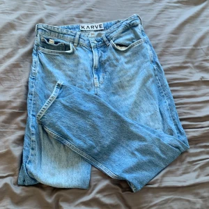 Blå jeans från Karve - Säljer ett par klassiska blå jeans från Karve. De har en straight passform med normal midja och är tillverkade i denim. Perfekta för en avslappnad stil. Det är ett hål ned hela sidan på vänstra fickan men inget som syns utanpå.