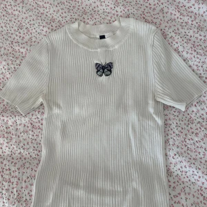 Ribbad tröja med fjäril - Ribbad tröja med fjäril från H&M divided i storlek XS. Har haft det ganska länge men är fortfarande i väldigt bra skick!