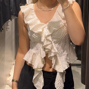 volangtopp från zara - superfin volangtopp från zara i en varm vit/beige färg! aldrig använts. storlek S men passar även för lite större byst