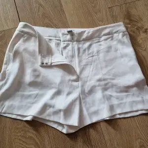 Säljer ett par stilrena vita shorts från H&M. De är högmidjade med en snygg passform och har knappar framtill. Perfekta för sommardagar eller en avslappnad fest. Materialet känns mjukt och bekvämt.