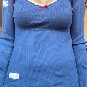 Blå ribbad tröja med spetsdetaljer - Säljer en superfin blå ribbad tröja från Odd Molly med lång ärm och en söt liten rosett framtill. Den har en v-ringad hals med vit spetskant som ger en gullig touch. Perfekt för både vardag och lite finare tillfällen. Tröjan är i bra skick och väldigt bekväm att ha på sig.🤗