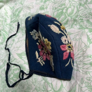 Hätta med blommor - Vacker fodrad hätta med broderade blommor och knytband. Mjuk vävd bomull.