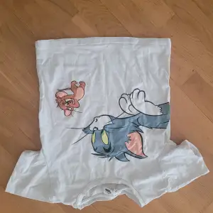 Säljer en supercool vit t-shirt från Shein med ett stort tryck av Tom och Jerry på framsidan. Perfekt för alla som älskar klassiska tecknade serier! T-shirten är i bomull och har en normal passform. Perfekt för vardagsbruk eller en avslappnad dag ute.