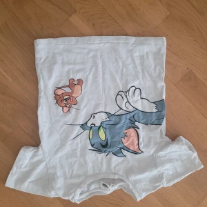 Vit t-shirt med Tom och Jerry från Shein - Säljer en supercool vit t-shirt från Shein med ett stort tryck av Tom och Jerry på framsidan. Perfekt för alla som älskar klassiska tecknade serier! T-shirten är i bomull och har en normal passform. Perfekt för vardagsbruk eller en avslappnad dag ute.