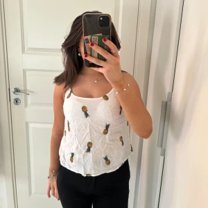 Vit linne med ananasmönster - Säljer ett superfint vitt linne med ett sött ananastryck över hela. Linnet är luftigt och skönt vilket passar perfekt till sommaren! Pris går att diskutera💕🍍