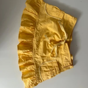 Gul kjol med volang - Säljer en superfin gul kjol med volangdetaljer. Kjolen har två fickor fram och ett knytband i midjan. Perfekt för sommaren och passar till både vardag och fest! 🌞
