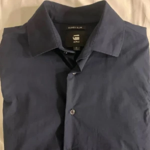Mörkblå skjorta från G-Star RAW - Säljer en snygg mörkblå skjorta från G-Star RAW i super slim passform. Skjortan har långa ärmar och knappar framtill. Perfekt för både vardag och fest!