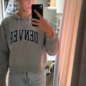Grå hoodie med 'DENVER' tryck - Säljer en superbekväm grå hoodie med texten 'DENVER' i mörkgrönt på framsidan. Den har en klassisk passform med långa ärmar och en justerbar huva med snören. Perfekt för en avslappnad stil eller mysiga dagar hemma. 🩶