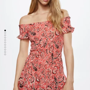 Mönstrad offshoulder klänning från MNG - Säljer en superfin offshoulder klänning från MNG i storlek XS. Den har ett färgglatt mönster i rött/korall och svart med volangdetaljer vid ärmarna. Klänningen är i nyskick och har en härlig passform som sitter bekvämt. Använd 1 gång.