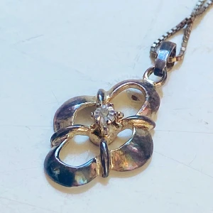 Silverhalsband med blomformad hängsmycke - Säljer ett elegant silverhalsband med ett unikt blomformat hängsmycke. Hängsmycket har en vacker design med en glittrande sten i mitten som ger en extra touch av glamour. Kedjan är tunn och smidig, perfekt för både vardag och fest. Ett måste för smyckesälskare! äkta silver och stämplat 925