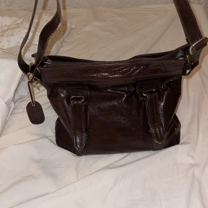 Brun axelväska i skinn från The Monte - Säljer en vintage brun axelväska i skinn från The Monte💕Väskan har flera praktiska fack med dragkedja och en justerbar axelrem! Perfekt till hösten😊Tveka inte att skriva om ni har någon fråga💌 Nypris: 2000kr!