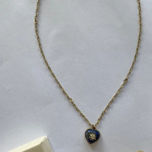 Guldhalsband med blått hjärthänge - Säljer ett guldhalsband med ett vackert blått hjärthänge. Hänget har en stjärndetalj i mitten <3 köpt på zalando för några år sedan