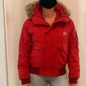 Röd vinterjacka från Helly Hansen - Säljer en snygg röd vinterjacka från Helly Hansen i storlek XS. Jackan har en mysig pälskantad huva och praktiska fickor framtill. Perfekt för kalla vinterdagar då den är super varm! Den är i bra skick och redo för nya äventyr. Passar perfekt till skidåkningen, jeans eller andra casual outfits. 🧥❄️