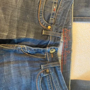 Blå jeans från Hilfiger Denim - Säljer ett par snygga blå jeans från Hilfiger Denim. De har en klassisk femficksdesign och en knappgylf. Jeansen är i bra skick och har en skön passform. Perfekta för både vardag och fest! Uppskattar storlek w25