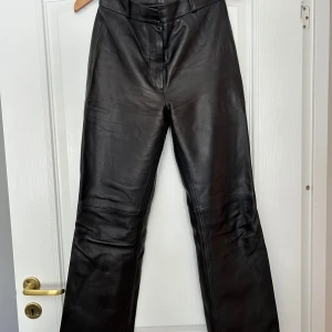 Svarta skinnbyxor från & Other Stories - Snygga svarta skinnbyxor från & Other Stories i storlek 36. De har en hög midja och en rak passform som ger en stilren look. Perfekta för höst och vinter, och kan enkelt kläs upp eller ner beroende på tillfälle. Byxorna är i nyskick och redo för nya äventyr!