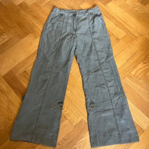 Grå / gröna byxor - Grå / gröna / khaki byxor. Bra skick (små skavanker). 79% Tencel & 21% Linne.  Lågmidjade och utsvängda / baggy. Hör av dig för bilder på! Ungefärliga mått:  Grenhöjd: 25cm Midja: 78cm Midja rakt över: 38cm Innerben: 76cm Hela byxans längd: 102cm. 
