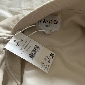 Jacka - Jacka i beige från Nakd, aldrig använd prislapp kvar. Nypris 1099kr i storlek 36