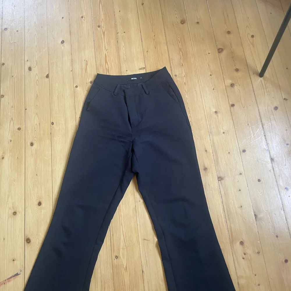 Snygga svarta kostymbyxor från Bik Bok i storlek 36. De har en klassisk design med raka ben och hög midja, perfekt för både jobb och fest. Byxorna är i fint skick och passar till alla tillfällen. Ett måste i garderoben för en stilren look!. Farkut & Housut.