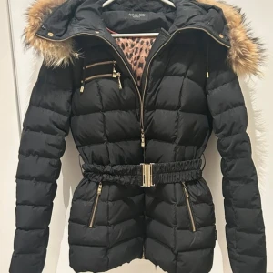 VARM Hollies jacka 36 - Hollies jacka med avtagbart bälte som ger en feminin look.   Jackan är i nyskick och har inga skavanker.  Storlek 36.