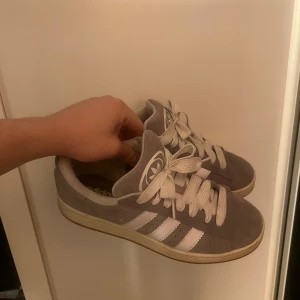 Grå Adidas sneakers med vita detaljer - Säljer ett par grå Adidas Campus 00 skick 9/10 men lite smutsiga därav de otroligt låga priset.