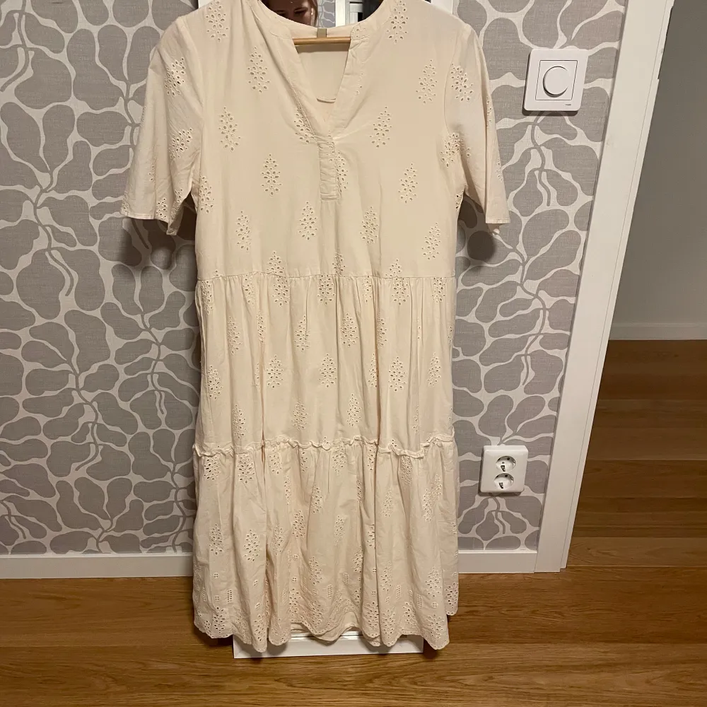 Säljer en söt beige klänning från Soyaconcept med korta ärmar och v-ringning. Klänningen har ett fint broderat mönster, ny med prislapp. Mekot.