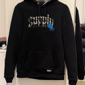 Svart hoodie från Supply & Demand - Snygg svart hoodie från Supply & Demand med tryck i grått och blått framtill. Bra pris för har använder fåtal gånger pris och frågar kan ni skriva till mig 