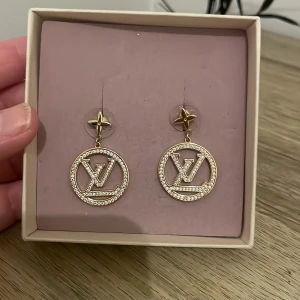 Guldörhängen med strassdetaljer - Eleganta guldörhängen med glittrande strassdetaljer och en stjärnformad topp. Perfekta för att ge en lyxig touch till din outfit.