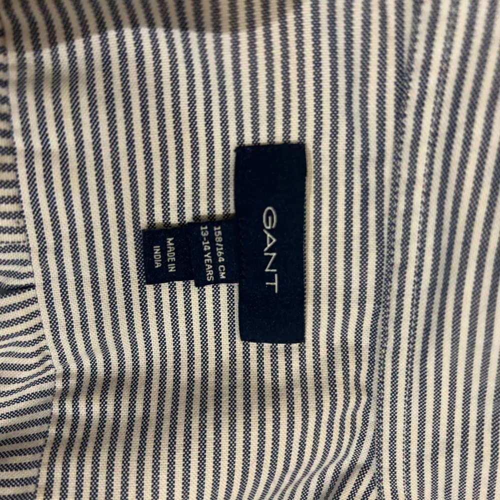 Snygg randig skjorta från GANT i blått och vitt. Skjortan har långa ärmar och knappar framtill. Perfekt för en stilren look.. Paidat.