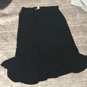 Svart långkjol - Elegant svart långkjol med en enkel och stilren design. Perfekt för att matcha med olika toppar och accessoarer. Kjolen har en mjuk och flödande passform som ger en bekväm känsla.