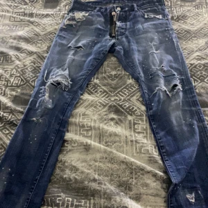 Dsquared2 äkta! - Snygga blå jeans från Dsquared2 med slitna detaljer och dragkedja. De har en modern look med flera revor och en cool finish. Perfekta för en trendig stil. Äkta!