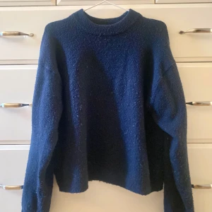 Mörkblå stickad tröja - Säljer en mysig mörkblå stickad tröja med rund halsringning. Tröjan har långa ärmar och en enkel design som passar perfekt för kyligare dagar. Perfekt för att hålla sig varm och stilren.