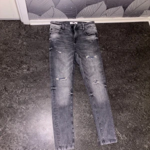 Grå jeans med slitningar - Snygga grå jeans från New Yorker med slitningar och en modern look. Ej använda. De har en slim passform och är tillverkade i jeansmaterial. Perfekta för en avslappnad stil. Nypris runt 250-300kr.