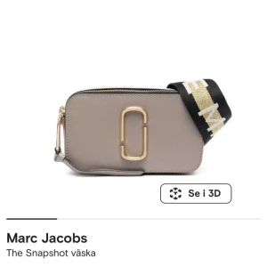 Marc Jacobs - Snygg och kompakt axelväska från Marc Jacobs i en stilren beige färg. Väskan har en bred axelrem med guldiga detaljer och en praktisk dragkedja. Perfekt för att bära dina viktigaste saker med stil.