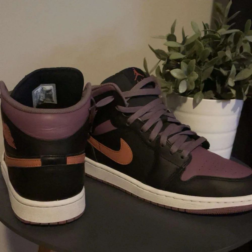 Snygga Nike Air sneakers i svart och lila med orange detaljer. Skorna har en klassisk design med snörning och en bekväm sula. Perfekta för dig som vill ha en stilren look med en färgklick. Inga skador och använda cirka 3 gånger. Pris kan diskuteras!. Kengät.