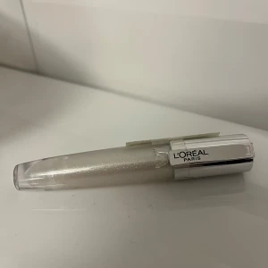 Transparent läppglans från L'Oréal Paris - Snyggt transparent läppglans från L'Oréal Paris med en skimrande finish. Perfekt för att ge dina läppar en glansig look. Kommer i en smidig tub med silverlock. Inte använd och ej öppnad. Försegling finns på produkten. Säljer för 90 kronor och jag köpte för den 144 kronor. 
