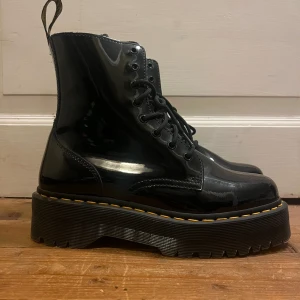 Dr martens  - Använda max 3 gånger. Modell: JADON PATENT PLATTFORMSKÄNGOR I LACKLÄDER Fakta: 	•	Sulans höjd: 3,8 cm 	•	Material: PU belagt läder                                         •  Storlek 42  Torka enkelt bort smuts med en fuktig trasa! Bara att höra av dig om du undrar något!