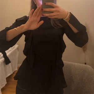 Blus - Svart blus med jätte fina volanger och knytning i midjan!