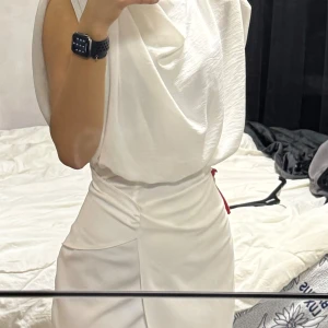 Vit klänning  - Elegant vit klänning med draperad design och öppen rygg. Klänningen har en figurnära passform och är ärmlös, vilket ger en stilren look. Perfekt för speciella tillfällen. Oanvänd med lappen kvar. Köpt från L&S i Malmö. Tyvärr passar inte den mig längre (drar in i midjan för att ge den en rättvis chans)  Inköpt för 999kr. 