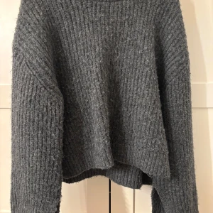Grå stickad tröja från Gina Tricot - Mysig grå stickad tröja från Gina Tricot i storlek M. Tröjan har en ribbad struktur och långa ärmar, perfekt för kyligare dagar. Enkel och stilren design som passar till det mesta.