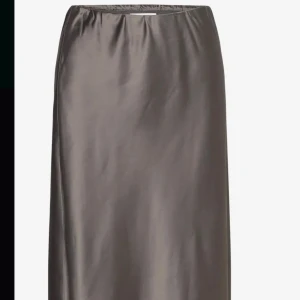 Mörk silver kjol från Stylein - Elegant mörk silver kjol från Stylein i en slät och glansig finish. Kjolen har en rak passform och är tillverkad i ett lyxigt material som ger en sofistikerad look. Perfekt för att höja din stilnivå. OBS: helt ny och oanvänd. Lappar sitter kvar. Ordinarie pris 2990kr