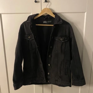 Svart jeansjacka från Zara - Snygg svart jeansjacka från Zara med klassisk design. Jackan har knappar framtill och två bröstfickor med knappstängning. Perfekt för en avslappnad stil.