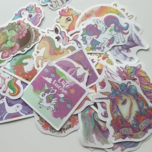30st Klistermärken med enhörningar - Ett set med färgglada klistermärken med enhörningstema. Innehåller olika motiv av enhörningar i regnbågsfärger, med blommor och fantasifulla bakgrunder. Perfekt för att dekorera anteckningsböcker, laptops eller andra ytor. Inkluderar både fyrkantiga och ovala former.