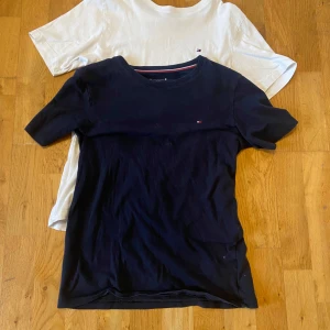 Svart och vit t-shirt från Tommy Hilfiger - Två stilrena t-shirts från Tommy Hilfiger i svart och vit. Båda är kortärmade och har en liten logga på bröstet. Perfekta för en avslappnad look.