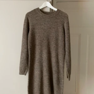 Stickad klänning - Jätte fin stickad klänning som är perfekt nu till hösten till en kappa och strumpbyxor. Den är i en biege brun färg. Är som ny, köpt på Pieces. Köpt för 400kr.