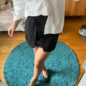 Svart kort kjol - Svart, kort kjol från bershka med omlott-detalj framtill!🤎 bekväm och supersnygg!💕