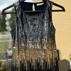 Svart och guld paljettlinne.  - Superglittrigt svart och guld paljettlinne. Nyskick! Perfekt för festliga tillfällen! Det är ärmlöst och har en snygg, rak passform. Baksidan är helt svart. Stl 158/164. Ca 13-15år Hämtas på Hägerstensåsen eller ök 🧡🖤