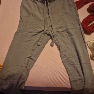 Grå byxor från H&M Divided - Säljer ett par grå byxor från H&M Divided. De är i storlek 34 (dam XS) och tillverkade av 100% viskos, vilket gör dem superbekväma och lätta. Byxorna har en avslappnad passform med knytband i midjan för en justerbar passform. Perfekta för en chill dag eller en avslappnad utflykt!