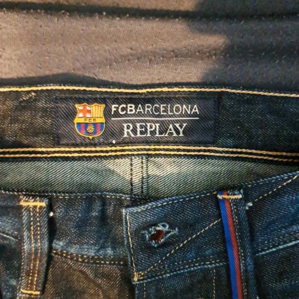 Säljer ett par snygga Replay Anbass jeans i mörkblå denim. De har ett coolt FC Barcelona-märke på insidan av midjan, vilket gör dem unika. Jeansen har en klassisk femficksdesign och en bekväm passform. Perfekta för både vardag och fest!. Jeans & Byxor.